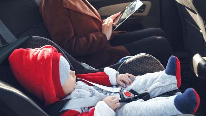 Mother with her small child in a baby car seat ride in the back seggiolini auto